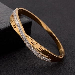 Crossed rose gold titanium bangle with Roman numerals and pavé crystals on a black box