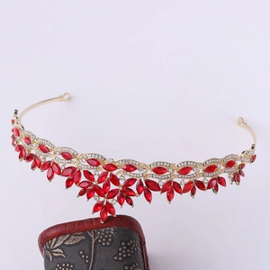 Macro detail of bridal crown with red rhinestones and gold leaf pattern on vintage base