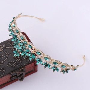 Detailed view of leaf crown with green crystals and gold metal on vintage wooden box