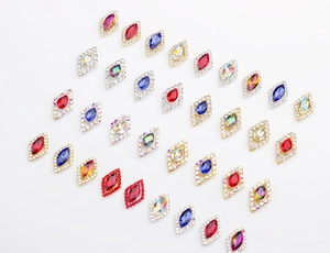 Macro shot of diamond-shaped nail art crystals with colorful gems and gold metal base