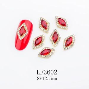 Detailed view of red marquise nail crystals with white rhinestones in gold setting