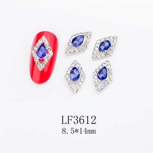 Macro detail of rhombus nail jewelry with blue teardrop crystals and white accents