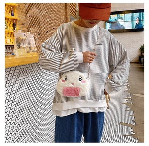 Model wearing cute plush rice ball crossbody bag with gold chain strap in cafe setting