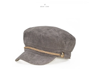 Detail of dark grey corduroy baker boy hat featuring gold braided rope and metal button