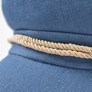 Close-up of blue corduroy octagonal hat with gold braided rope and twill texture
