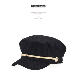 Detailed texture of black corduroy baker boy hat with golden rope and vintage metal button