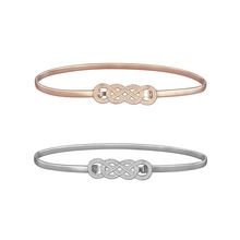 Detail of rose gold and silver open bangles with an infinity knot design on white background