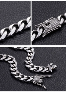 Macro detail of silver Cuban link chain with crystal box clasp on black leather background