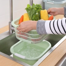 Close-up of light green kitchen drain basket being used to wash fresh vegetables under water