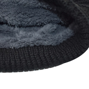 Close-up detail of thermal fleece lining and black cable knit fabric on a winter beanie