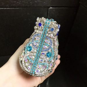 Detail of owl shaped evening clutch bag featuring blue crystals and silver metal frame