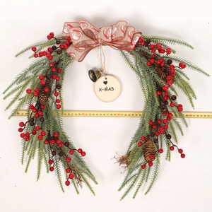 Detail of Christmas wreath with pine needles, red berries, pine cones and a burlap bow