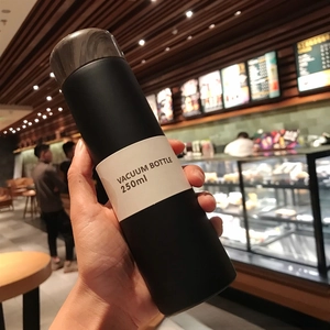 Hand holding a matte black 250ml vacuum flask with a minimalist wood grain lid