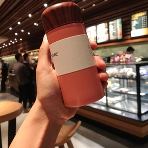 Close-up of 150ml pink mini vacuum flask with wood grain lid held in hand