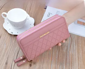 Detailed macro view of pink quilted leather texture with double zippers and wristlet strap