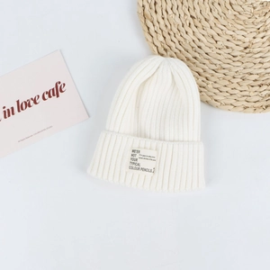 Close-up of ribbed knit beanie in off-white featuring a stylish woven textile label