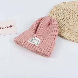 Detailed macro shot of a pink knitted beanie with a folded brim and stylish white fabric label