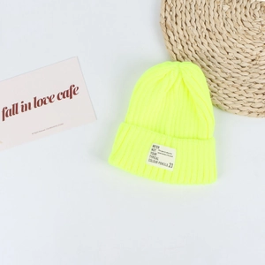 Close-up of neon yellow ribbed knit beanie with stylish white lettered woven label