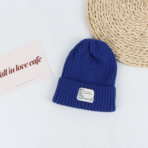Close-up of a royal blue ribbed knit beanie featuring a white fabric brand label on the fold