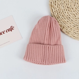 Detailed view of pink ribbed knit beanie with soft texture on a decorative straw mat