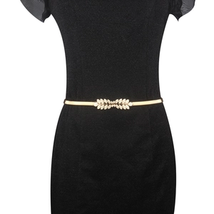 Close-up of golden leaf buckle skinny belt styled on a black dress for women