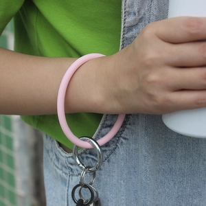 Pink silicone bangle keychain with silver metal ring shown worn on a wrist