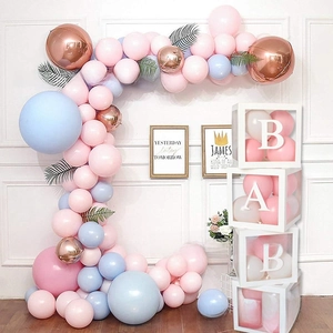 Detailed view of white baby shower balloon boxes with pink balloons and green leaves decor