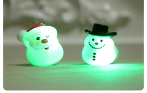 Detail shot of glowing Santa and Snowman LED rings emitting a soft green festive light