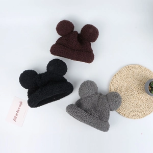 Three plush knitted winter hats for children with cute round ears in brown, black, and gray