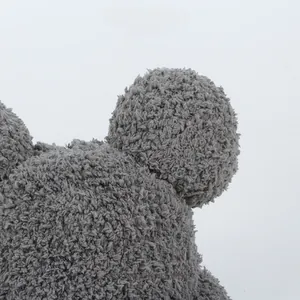 Close-up of grey plush fleece children's winter hat with cute round pom-pom ears