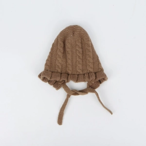 Detail of coffee brown knit baby hat featuring cable stitch patterns and ruffled edges