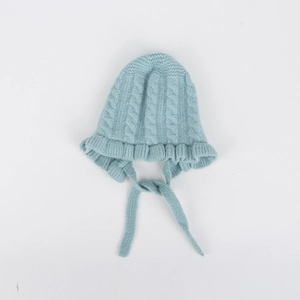 Detail view of baby knit bonnet featuring cable stitch pattern and ruffled edges in light blue