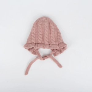 Detail of pink knitted baby hat with ruffled edges and cable knit texture pattern