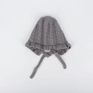Detail of grey cable knit baby bonnet with ruffle trim and soft textured yarn