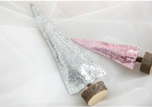 Close-up of glitter-coated pink and silver mini Christmas trees with natural wood bases
