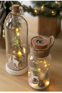 Close-up of glass Christmas jars with LED lights, pine cones, and reindeer decorations