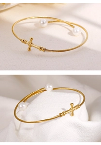 Detailed macro of gold twisted cable bracelet featuring cross charm and white pearls