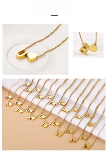 Macro detail of 18K gold plated heart and letter charms on stainless steel chain
