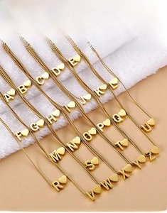 Detail shot of 26 gold heart letter necklaces on a soft fur background in close-up view