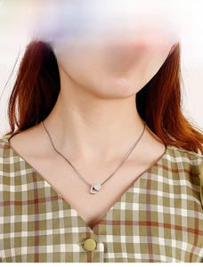 Detail of silver heart and letter L pendant necklace on model with plaid shirt