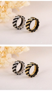 Detail view of two-tone rotating gear rings in silver and gold titanium steel on a beige surface