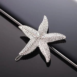 Silver metal starfish hair clip with white sparkling rhinestones on a black reflective surface