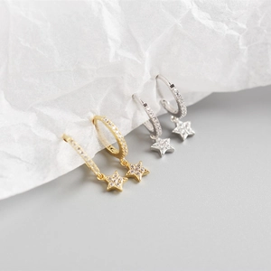 Detail of star-shaped hoop earrings in gold and silver finish with sparkling CZ stones
