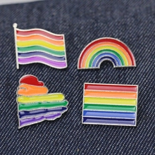 Set of four colorful enamel lapel pins with rainbow motifs on dark denim fabric background
