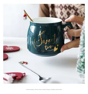 Detail of dark green Christmas mug with Sweet Times text and two hanging pendant spoons