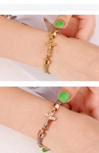 Detailed view of gold and rose gold mesh strap bracelets with Greek key cross charms