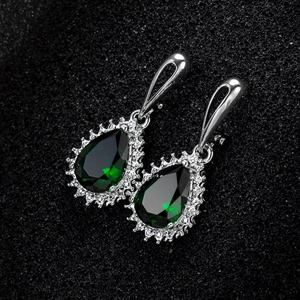 Macro shot of silver teardrop earrings featuring emerald green cubic zirconia stones