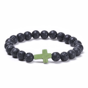 Close-up of black lava stone beaded bracelet with a green turquoise cross charm detail
