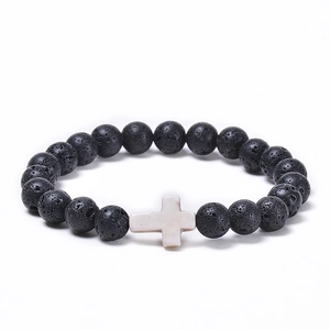 Detail of porous black lava stone beads and white turquoise cross on elastic bracelet