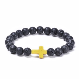 Close-up of black lava rock beads and yellow cross pendant on elastic bracelet
